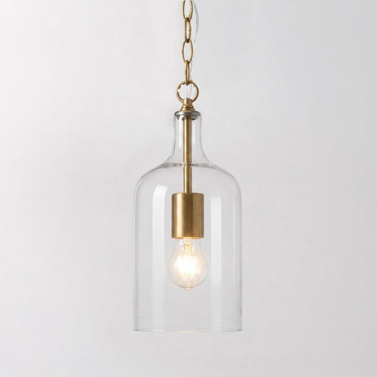 Gold pendant light with clear glass bell shade and visible warm bulb