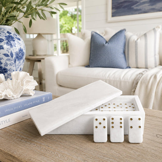 Open white domino case with gold-dot tiles on table surface