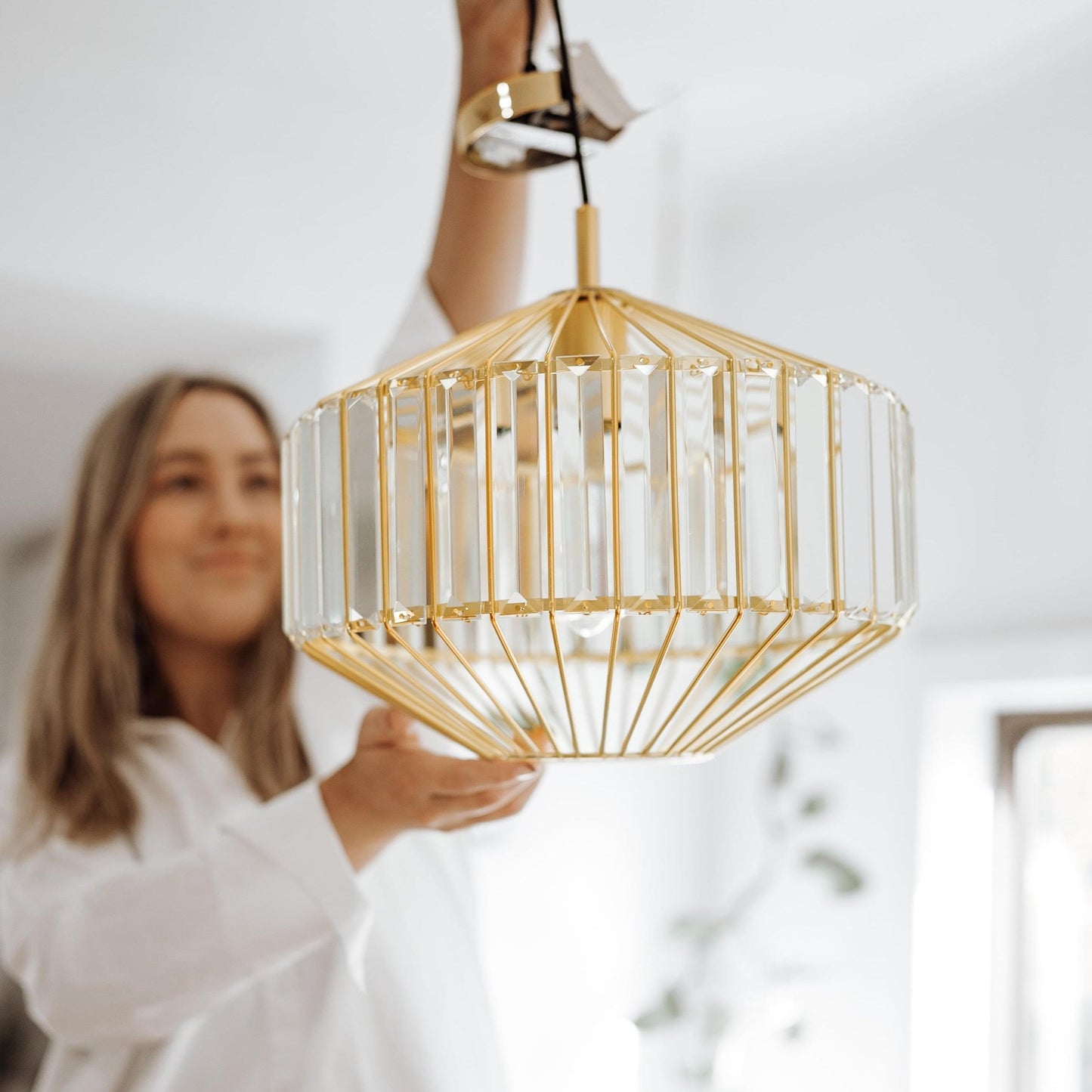 Gold prism glass pendant light with faceted clear panels, close-up view of shade