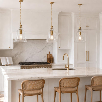 Gold bell pendant light with clear glass shade and hanging chain, above a counter.
