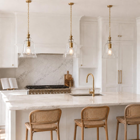Gold bell pendant light with clear glass shade and hanging chain, above a counter.