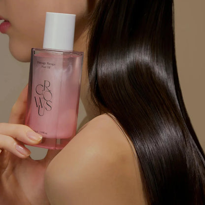Hair oil bottle held beside long dark hair, glossy smooth hair texture
