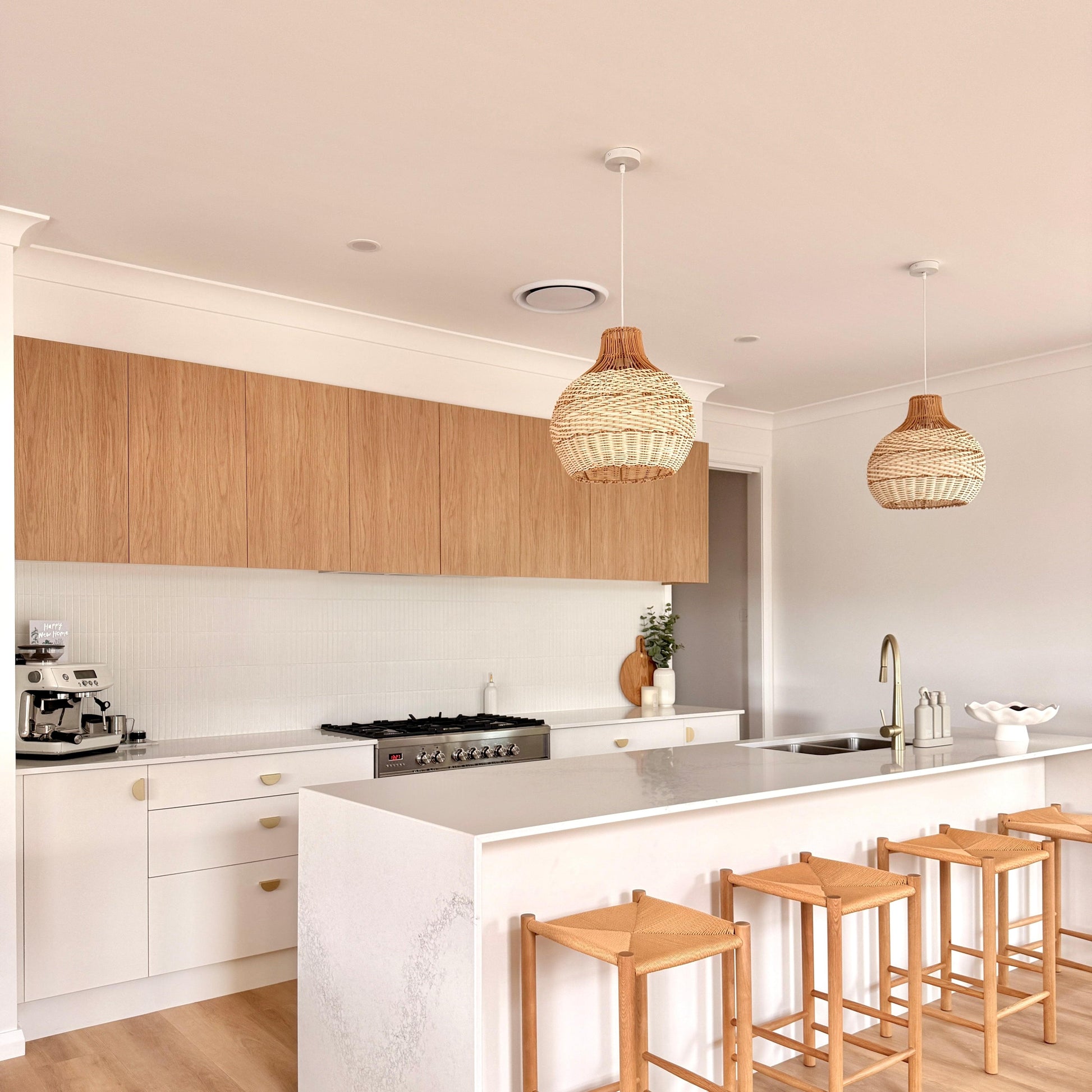 Natural rattan pendant light set with woven teardrop shades over kitchen counter
