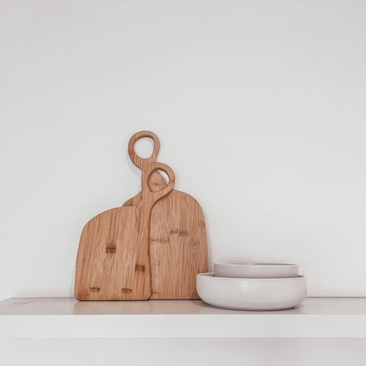 Two bamboo chopping boards with loop handles on tabletop