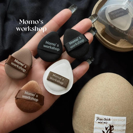 Mini makeup puffs in hand: black, brown, and white teardrop sponges