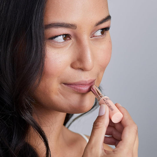 Peach DHC lip cream balm being applied on lips from a small tube