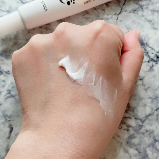 White eye cream on fingertip swatch on skin, visible thick cream texture