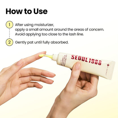 Eye cream tube held in hands with small yellow cream on fingertips