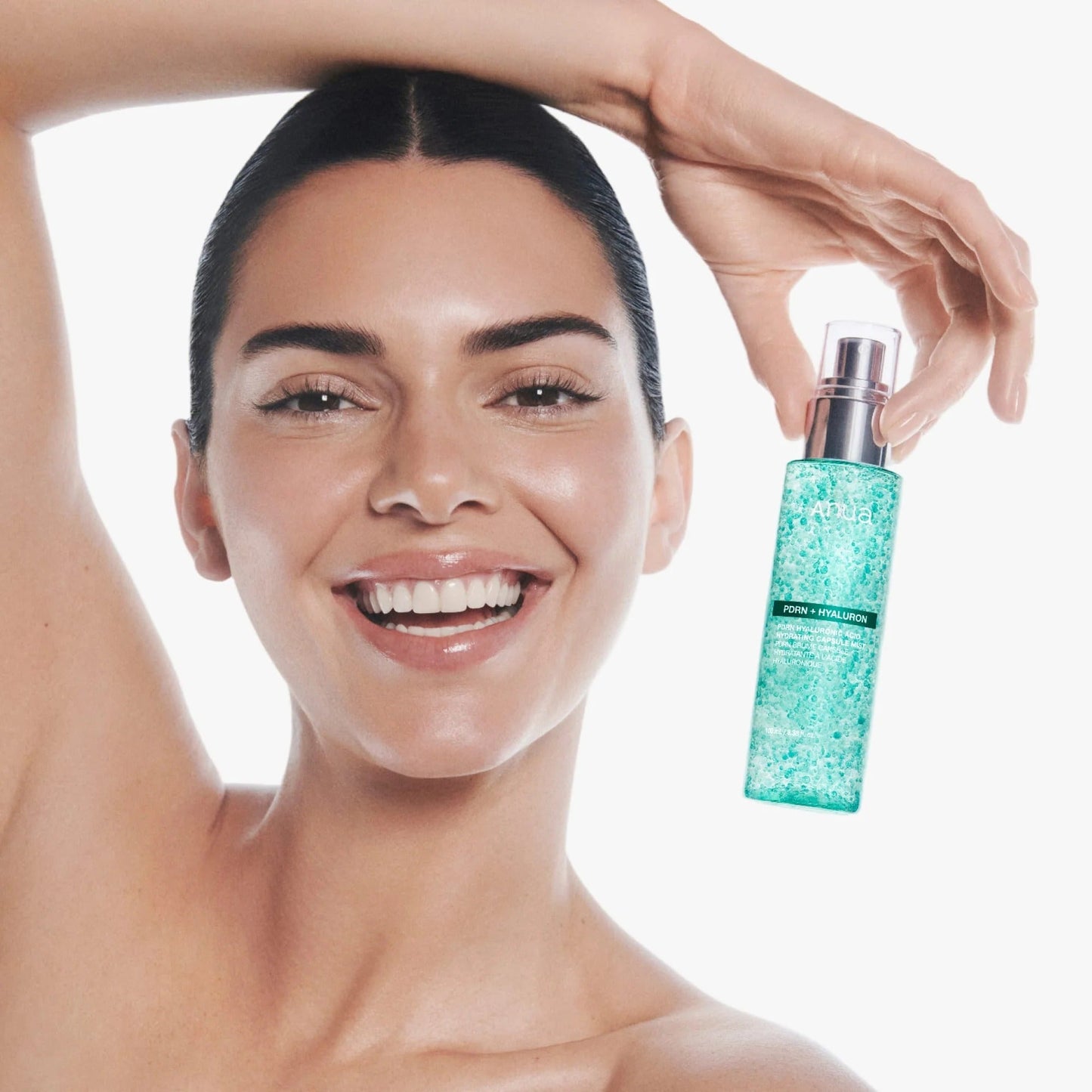 Anua mist bottle with silver pump and teal aqua liquid, held in a hand