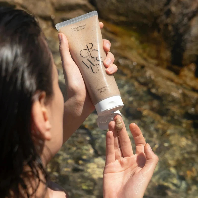 Scalp scrub tube application near hairline with hands holding creamy paste