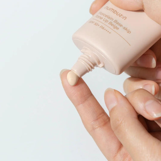 Beige sunscreen base-skip tone-up cream being squeezed onto fingers from tube, SPF50