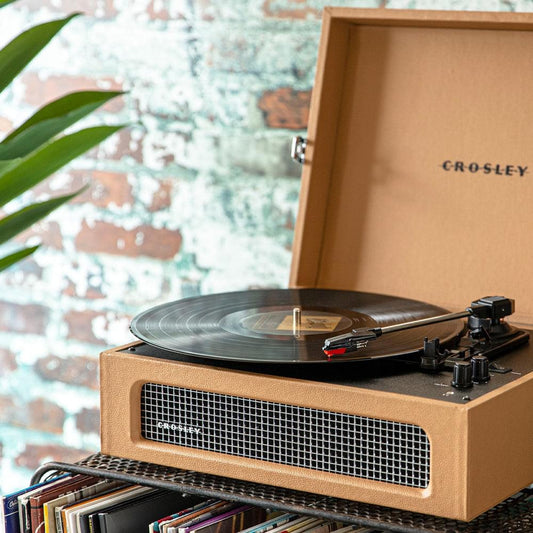 Tan portable turntable with lid open, record on the spinning platter