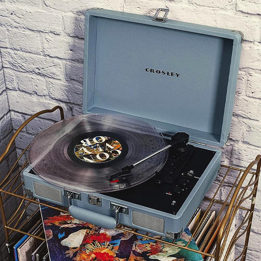 Light-blue portable turntable on a table, vinyl record on platter with tonearm