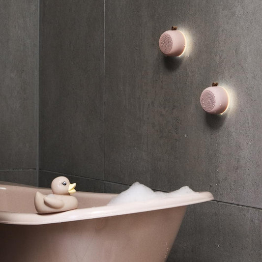 Dusty rose Bluetooth speaker pair mounted on wall, round with fabric mesh grille