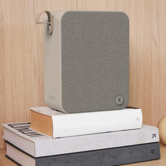 Kreafunk Aboom+ Bluetooth speaker with grey fabric grille, ivory sand body, side handle