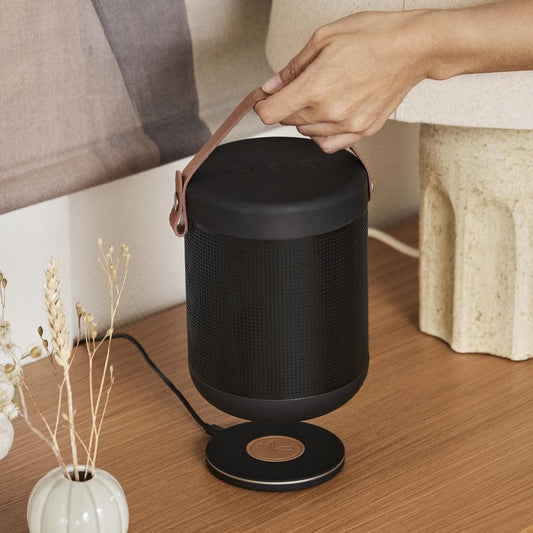 Black Bluetooth speaker with leather handle, standing on a circular base
