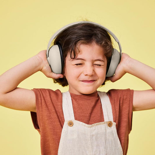 Kids ear muffs in ivory-beige with black cushioned ear pads, worn by child