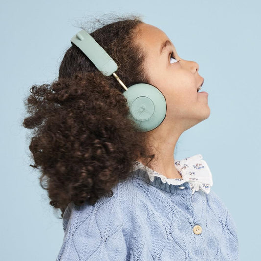 Kids Bluetooth headphones in dusty green on child, round earcups and padded headband