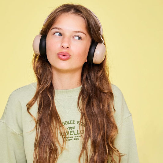 Kids over-ear headphones in ivory with black ear cushions worn by woman
