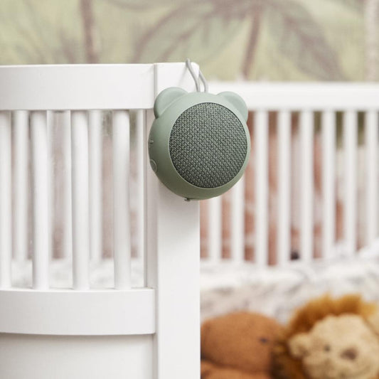 Dusty green bear-ear Bluetooth speaker clipped to a crib rail