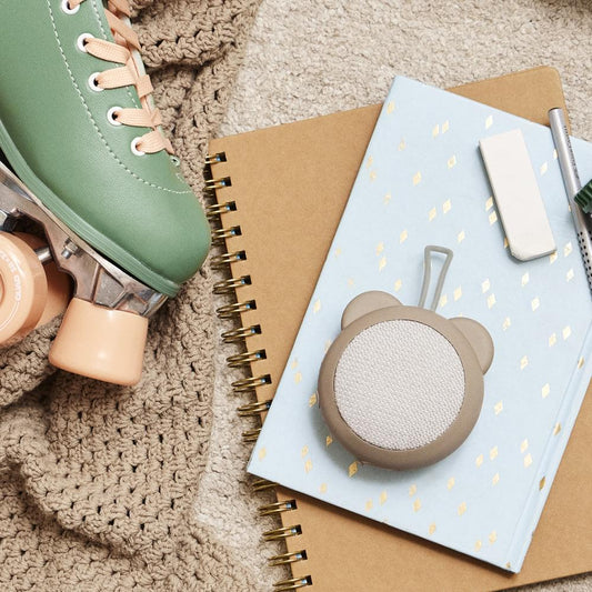 Ivory bear-ear Bluetooth speaker with textured fabric grille and top hanging loop.