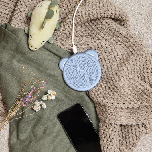 Light blue kids wireless Qi charger on blanket with connected charging cable