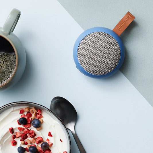Fabric Bluetooth speaker with blue body and gray woven top, leather strap detail