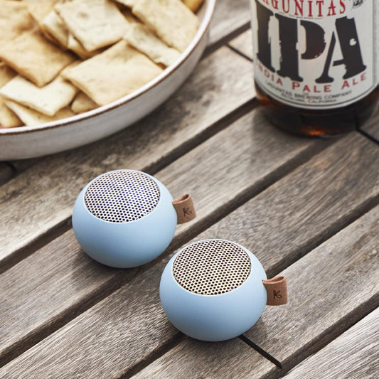 Two cloudy blue mini Bluetooth speakers, each with perforated grille and fabric loop