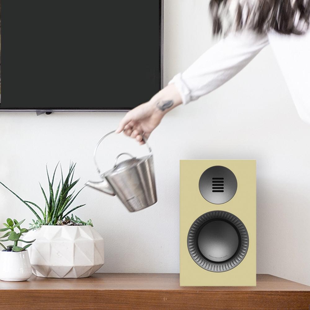 Butter powered speaker standing on floor with black woofer and gunmetal tweeter grille