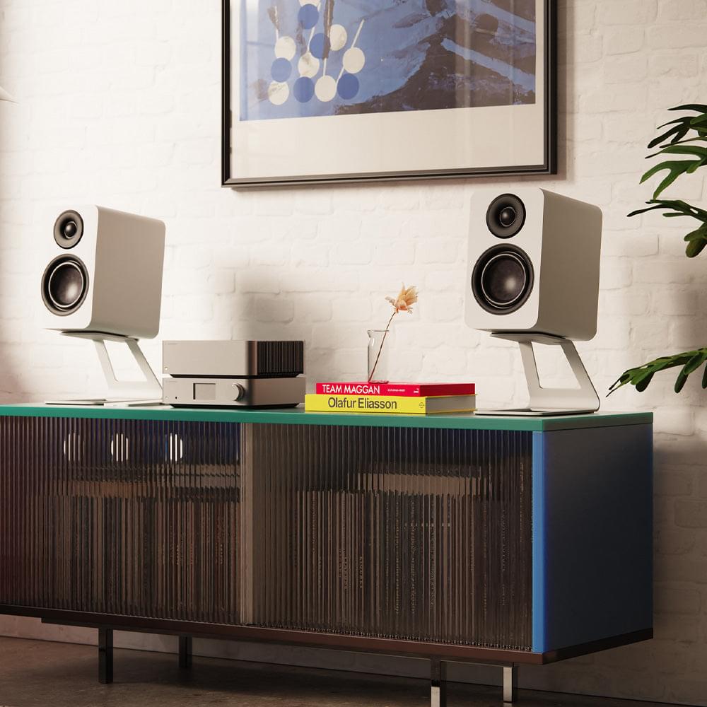 Matte white passive bookshelf speakers on a media console with black drivers