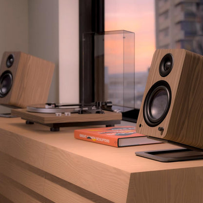 Matte walnut powered bookshelf speaker with black tweeter and woofer, side view
