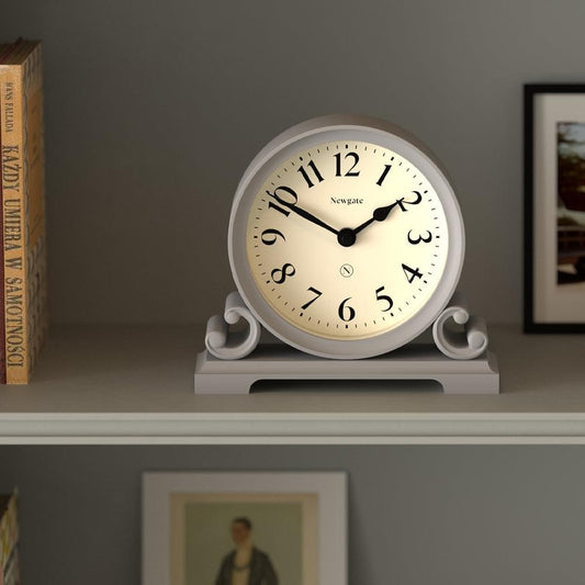 Grey mantel clock angled view, cream dial with Roman-style numerals and Newgate branding