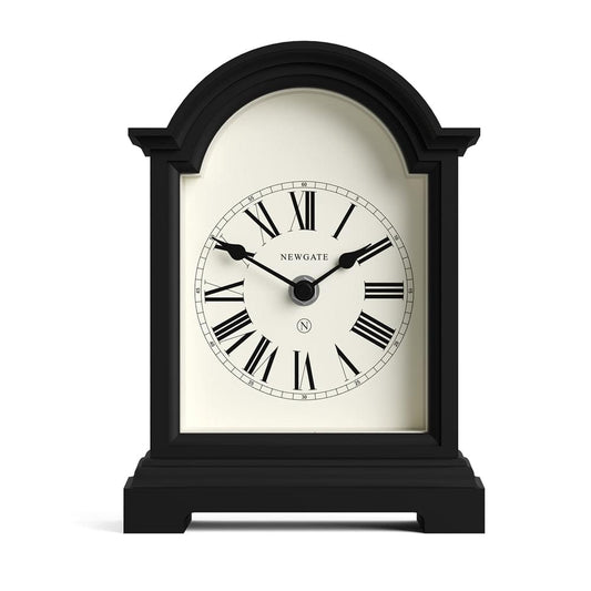 Black mantel clock with arched glass front, cream dial, Roman numerals, and black hands