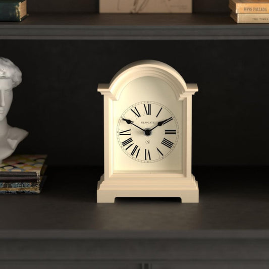 Vanilla cream mantel clock on tabletop with Roman numeral dial and black hands