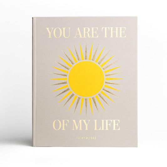 Beige photo album with yellow sun graphic and gold lettering on the cover