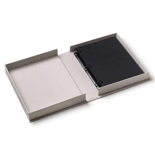 Opened photo album showing black inner cover and metal ring binding in gray case