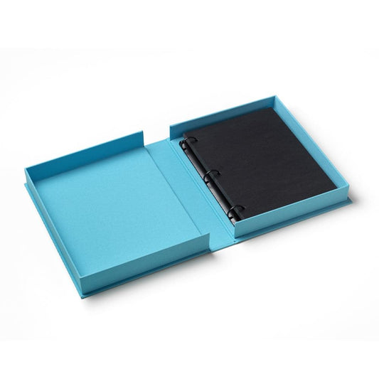 Turquoise photo album open with black photo pages and stitched spine