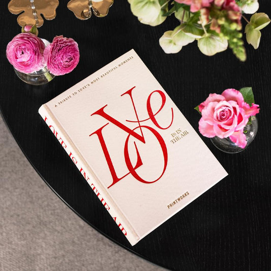 Beige photo book with red typographic cover, angled view
