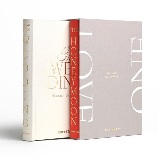 Two wedding photo books, beige and gray covers with red spine and “LOVE” lettering