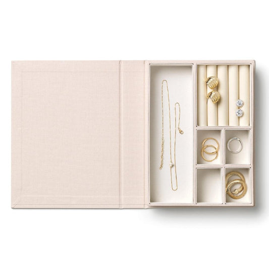 Open beige jewelry box with divided compartments holding necklace chain and rings