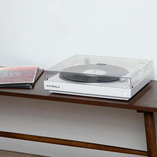 White turntable on table with black record and clear dust cover