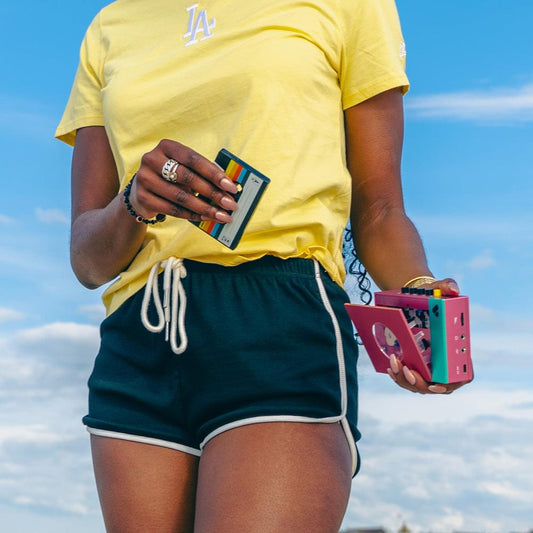 Pink and teal portable cassette player/recorder held near chest with visible knobs