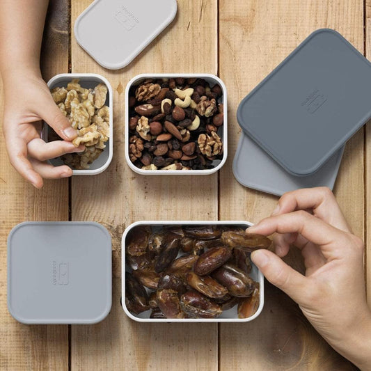 Three-compartment bento container with grey-blue lid, open to show food