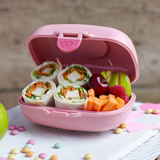 Monbento pink kids snack box, open with fruit and roll-ups in sections.