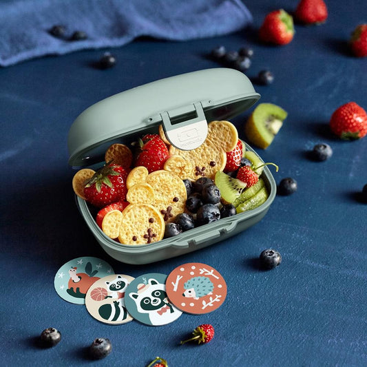 Light green kids snack box with open lid and fruit and cereal snacks inside