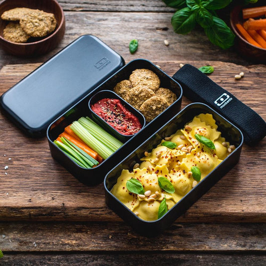 Black bento box with lid open and three food compartments, meal prep containers