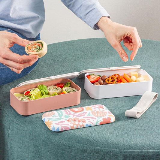 Open bento box on table with two filled compartments and gray lid strap