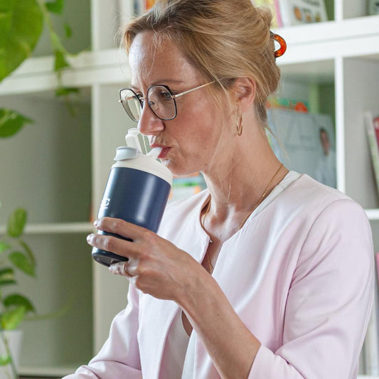 Blue travel mug with lid held in hand