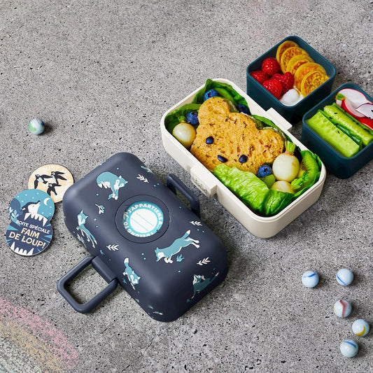 Kids bento box, dark blue lid with dinosaur pattern, open with compartments and food