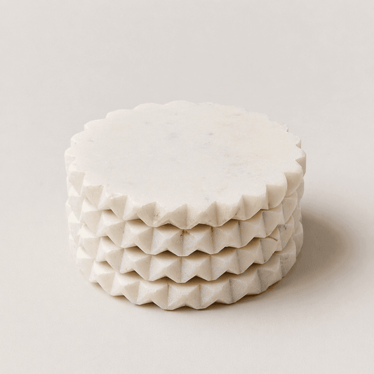 White marble coaster with jagged scalloped edge, round top and stacked ridged layers